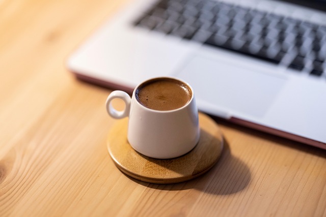 person reviewing expenses on laptop with Chilean peso notes and coffee